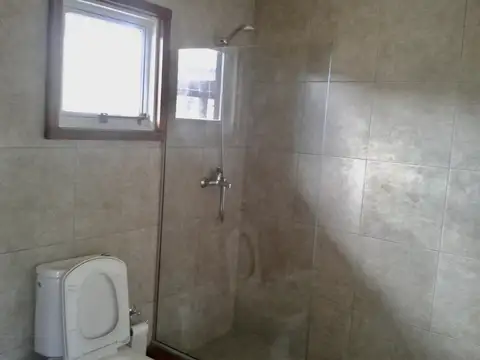 Hermosa casa PH de tres ambientes, con entrada pasante de auto, cochera semi cubierta y amplio jardín libre.