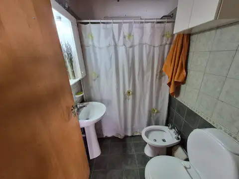 Amplia casa en PH de cuatro ambientes, en dos plantas, con garage y jardín libre al frente y al fondo. Incluye un espacio adicional con potencial para local comercial.