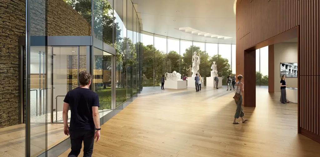 Imagen de una sala de exposiciones en el Centro Cultural Lola Mora, donde los visitantes admiran esculturas a través de grandes ventanales de vidrio que ofrecen vistas al entorno natural. El interior presenta suelos de madera y paredes de vidrio que conectan el espacio con el exterior.